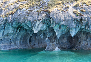 Interior of the flooded Marble Caves, unique rock formations in the General Carrera Lake, Chile. The walls of the caves have swirling mineral patterns. Turquoise water fills the caves with blue light.