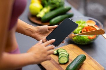 Weight Loss Application. Unrecognizable Woman Using Mobile Phone With Empty Screen, Cooking And Searching Recipes For Slimming Preparing Healthy Dinner In Modern Kitchen At Home. Cropped, Mockup