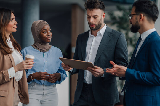 Business team discussing work using digital tablet in office lobby