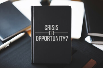 Black notebook with text Crisis or Opportunity, surrounded by other notebooks and pen, showcasing business decision-making concept