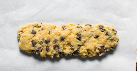 overhead view of chocolate chip biscotti dough on parchment paper, chocolate chip cantucci cookie dough on parchment lined baking tray