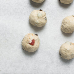Hot cross bun dough being cut into pieces on a marble countertop, process of making hot cross buns