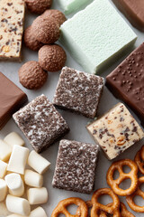 Assorted confections displayed in an array, featuring chocolate, mint, and nut varieties, with pretzels and marshmallows. Textured surfaces create a visually appealing contrast