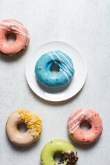 Overhead view of glazed donuts on a white countertop, top view of homemade pastel doughnuts, process of making Easter glazed doughnuts