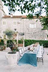 Laid long table with chairs stands in the garden near the wedding rotunda