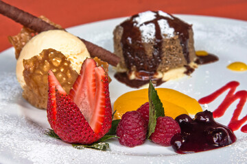 Delicious chocolate fondant with red berries and peach with vanilla ice cream, desserts