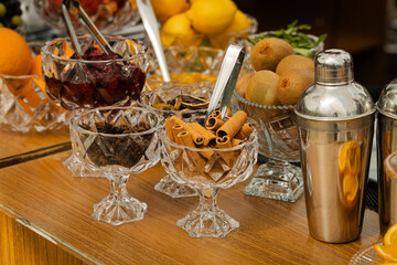 Frutas coloridas e coqueteleiras elegantes se encontram na mesa de drinks, convidando ao brinde com charme e frescor.
