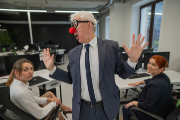 Obraz premium An elderly man in a clown costume fools around at work.