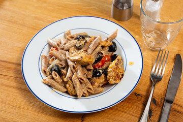 Appetizing pasta with chicken and vegetables pieces served on plate