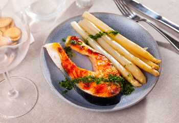 Mediterranean cuisine, roasted sliced tasty salmon with asparagus on a table in a cafe