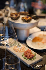 Champagne tasting, Wine glasses are on the table, stylish table setting, wine is poured from a bottle and decanter, sparkling wine bubbles, snacks, people smell the aroma and taste the wine