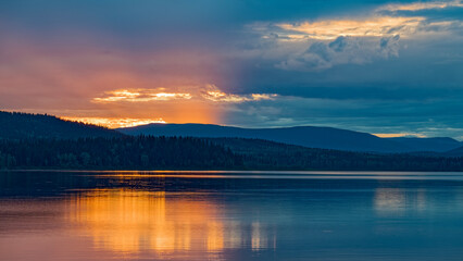 Fototapeta premium A deep orange lit sky at sunset over McLeod Lake at Whiskers Point Provincial Park, British Columbia, Canada