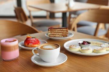 Delicious cottage cheese pancakes, desserts and aromatic coffee served on wooden table in cafe