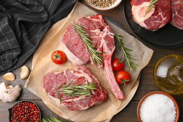 Pieces of raw beef, products and spices on wooden table, flat lay