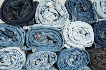 Different stylish rolled jeans as background, top view