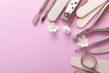 Set of different manicure tools and flowers on pink background, flat lay. Space for text