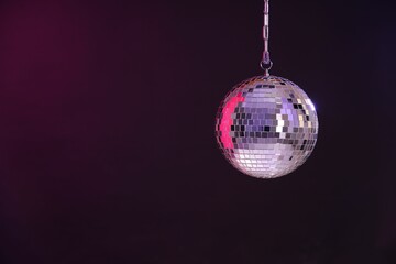 Shiny disco ball on dark purple background, space for text