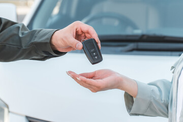 女性客に車の鍵を渡す自動車整備士の男性スタッフ
