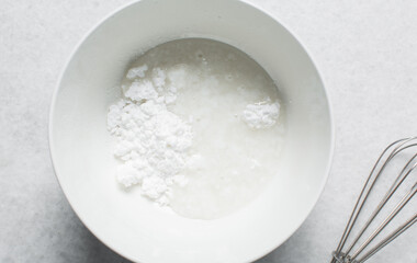 Overhead view of icing sugar mixed with water, powdered sugar dissolved in water on a white table