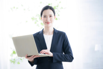 ノートパソコンを持つビジネスウーマン　カメラ目線で笑顔