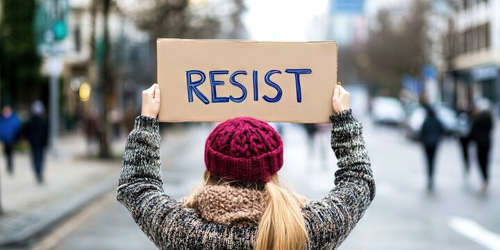 woman holding sign "RESIST" text on sign