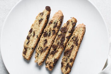 Overhead view of chocolate chip biscotti on white parchment lined tray, top view of chocolate chip cantucci cookies on a white board