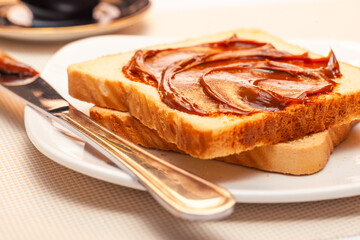 A close-up of a slice of bread with dulce de leche cream on top. Tilted view.
