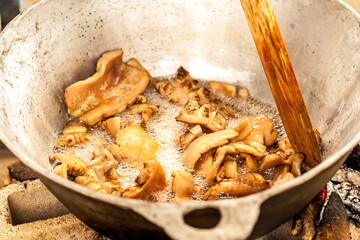 Close-up shot. Process of making pork rinds in a metal pot.