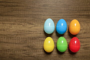 close-up flat lay of plastic red, blue, green yellow and orange Easter eggs in a group against a wooden background with copy space 