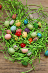 colorful jellybeans scattered with green Easter grass in a pile against a wooden background
