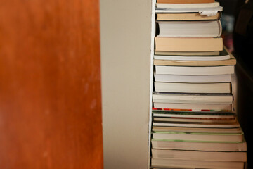 close-up of a stack of used books in a variety of sizes against an off-white wall in an interior
