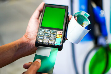 Photo of a gas station employee using a Mobile EDC machine to swipe membership cards and credit cards at a gas station, Thailand. © Nattawat