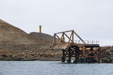 A bridge is in the water with a lighthouse in the background