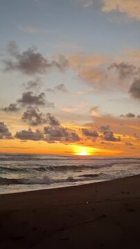 The beauty of the orange sky at sunset over the crashing waves of the black sand beach