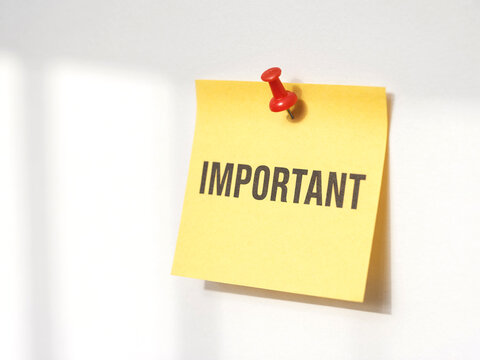 Important reminder note pinned on wall with red pin for urgent tasks and announcements message board