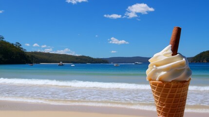 Hand holding vanilla soft serve ice cream cone with cinnamon stick on a sunny beach day at Pandy Bay, overlooking blue sea, white clouds, crashing waves, and distant boats for a relaxing summer treat.