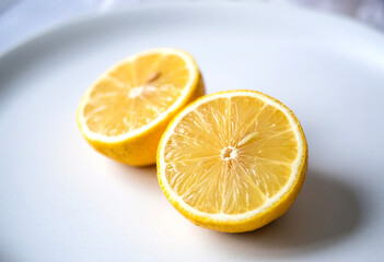 Fresh lemon halves on a white plate for cooking and baking ingredients stock photo and product image