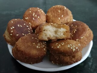 Golden-brown, sesame-topped Khasta pastries served on a white plate. Crisp outside, soft inside—perfectly fried and visually tempting on a dark granite backdrop.
