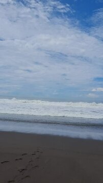 Waves Crashing on a Black Sand Beach Under a Bright Blue Sky
