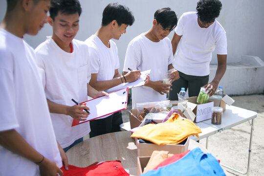 Diverse Men Collect Food and Clothes to Take Them to People in Refugee Shelters - Powered by Adobe