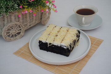 a delicious serving of chocolate sponge cake topped with a generous layer of grated cheese and a thin spread of white cream