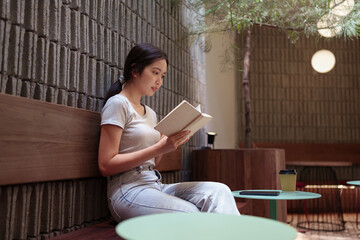 Peaceful young woman reading her diary and reflecting during quiet moment at serene outdoor cafe