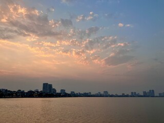 Pastel Dawn: Soft Urban Skyline Meets Gentle Cloud Formations on West Lake in Hanoi, Vietnam