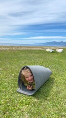 Fun games in nature little girl wrapped carpet