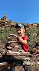 Little boy builds a pyramid of stones in the mountains