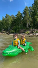 small children on an inflatable crocodile swim in the sea