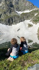 Children sit on potties on the shore of a lake in the mountains
