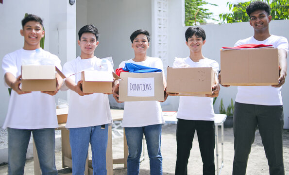 Male Volunteers Holding Box with Food and Clothes in Charity Center