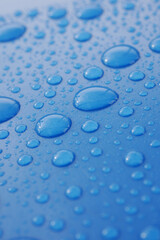 Close-up view of water droplets on a blue surface reflecting light