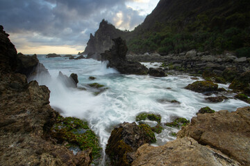The view of the sun is tangible at Watu Lumbung Beach, Gunung Kidul, with the crashing waves hitting the coral rocks.